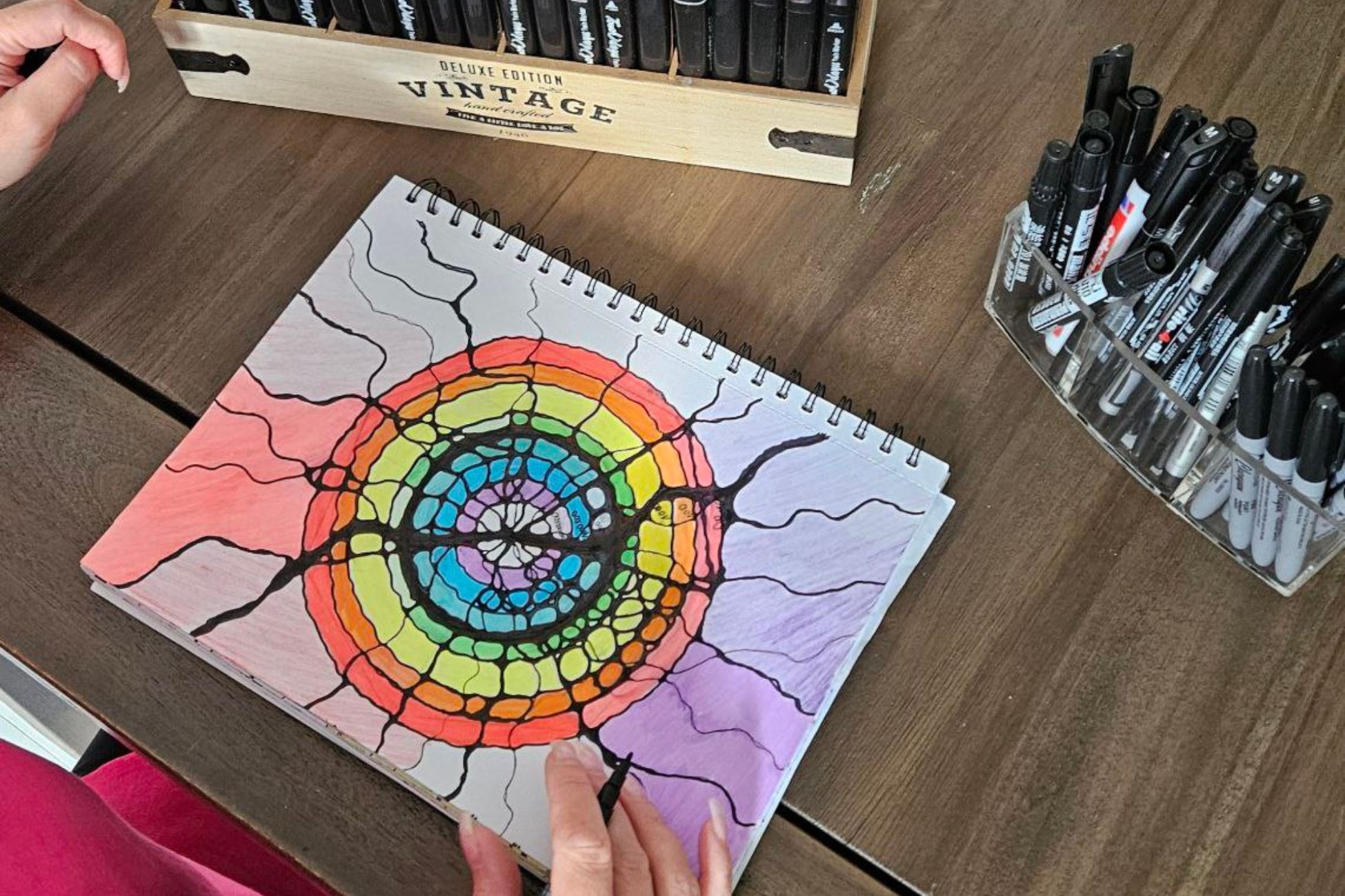 Kolorowa mandala neurograficzna tworzona przy biurku.